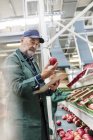 Manager mit Klemmbrett inspiziert rote Äpfel in Lebensmittelverarbeitungsbetrieb — Stockfoto