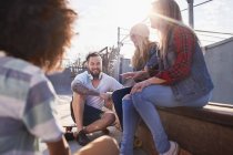 Friends with skateboards hanging out and talking at sunny skate park — Stock Photo