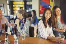 Mujeres sonriendo al camarero y bebiendo en el bar - foto de stock