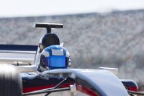 Fórmula um piloto de carro de corrida usando capacete na pista de esportes — Fotografia de Stock