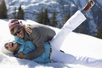 Exuberant couple laying in snow — Stock Photo