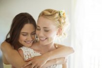 Красивая подружка невесты обнимает невесту в спальне — стоковое фото