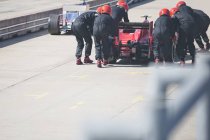 Pit crew pushing formula one race car out of pit lane — Stock Photo