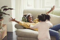 Энтузиастская мать на диване приветствует бегущую дочь — стоковое фото