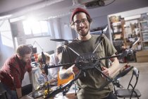 Portrait smiling male designer holding drone in workshop — Stock Photo