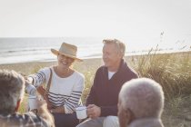 Parejas mayores tomando café en la playa soleada - foto de stock