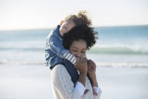 Mère portant sa fille sur ses épaules sur la plage — Photo de stock