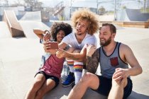 Amici maschi con fotocamera telefono scattare selfie a soleggiato skate park — Foto stock