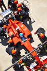 Équipage aérien remplaçant les pneus d'une voiture de course de formule 1 dans la voie de la fosse — Photo de stock