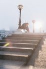Мужчина бегун завязывает обувь на солнечном городском фонарном столбе — стоковое фото