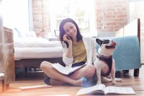 Woman talking on cell phone next to French Bulldog on floor — Stock Photo