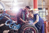 Motorradmechaniker reparieren Motorrad in Werkstatt — Stockfoto