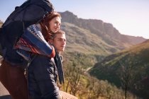 Affectueux jeune couple avec sac à dos randonnée, faire une pause dans un paysage ensoleillé — Photo de stock
