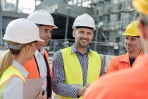 Усміхнені інженери та будівельники зустрічаються на будівельному майданчику — стокове фото