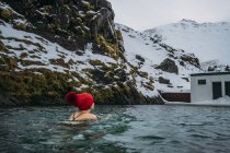 Mujer en media gorra nadando por debajo de montañas nevadas, Islandia - foto de stock