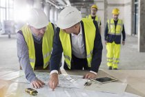 Інженери-чоловіки обговорюють креслення на будівельному майданчику — стокове фото