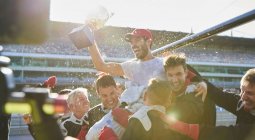 Formula one racing team carrying driver with trophy on shoulders, celebrating victory — Stock Photo
