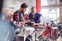 Male motorcycle mechanics repairing part in workshop — Stock Photo