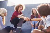 Friends with skateboards handshaking at sunny skate park — Stock Photo