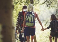 Mother and daughter with backpacks holding hands hiking in woods — Stock Photo