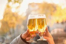 Close up couple toasting beer glasses at autumn cafe — Stock Photo