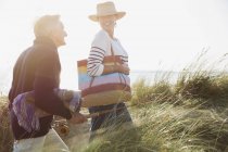 Молодая пара с удочкой гуляет по траве солнечного пляжа — стоковое фото