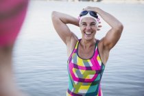 Femmina nuotatore sorridente guardando la fotocamera sulla riva — Foto stock