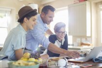 Mid adult man with teenage boys using laptop in kitchen — Stock Photo