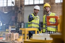 Travailleurs de l'acier parlant et pointant dans l'usine — Photo de stock