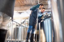 Male brewers checking vat in brewery — Stock Photo