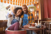 Porträt lächelnd, liebevolles junges Paar, das sich im Café umarmt — Stockfoto