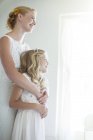 Bride embracing bridesmaid and looking out of window — Stock Photo
