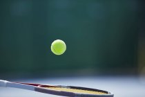 Тенісний м'яч підстрибує на тенісній ракетці — стокове фото