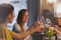 Улыбающиеся подруги пьют бокалы с белым вином в ресторане — стоковое фото