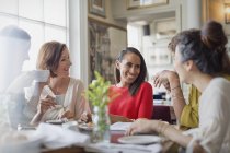 Mujeres sonrientes amigas cenando tomando café en la mesa del restaurante - foto de stock