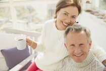 Портрет улыбающейся зрелой пары, обнимающей и пьющей кофе — стоковое фото