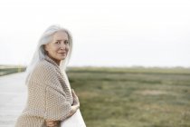 Retrato confiado mujer mayor apoyada en barandilla de paseo marítimo - foto de stock