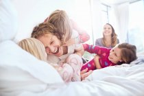 Brincalhão pai e filhas cócegas na cama — Fotografia de Stock
