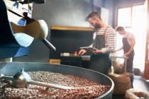 Male coffee roasters behind roasting coffee beans — Stock Photo