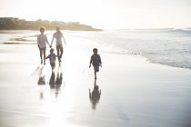 Familie spaziert bei Sonnenuntergang am Strand — Stockfoto