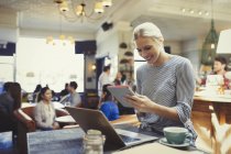 Smiling creative businesswoman using digital tablet and laptop in cafe — Stock Photo