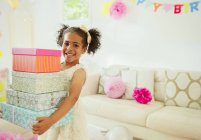 Portrait smiling girl carrying stack of birthday gifts — Stock Photo