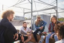 Friends hanging out and talking at sunny skate park — Stock Photo