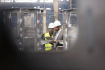 Gerente y trabajador del acero con la reunión del portapapeles en fábrica - foto de stock