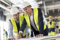 Чоловіки-інженери, які переглядають креслення на будівельному майданчику — стокове фото