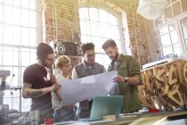Young designers examining blueprints in workshop — Stock Photo