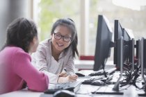 Meninas estudantes sorrindo pesquisando no computador em sala de aula de laboratório — Fotografia de Stock