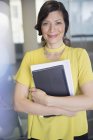 Portrait smiling, confident businesswoman with digital tablet and paperwork — Stock Photo