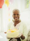 Retrato sorrindo sênior mulher segurando bolo de aniversário — Fotografia de Stock