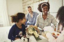 Daughters bringing Mothers Day flowers and breakfast to mother in bed — Stock Photo